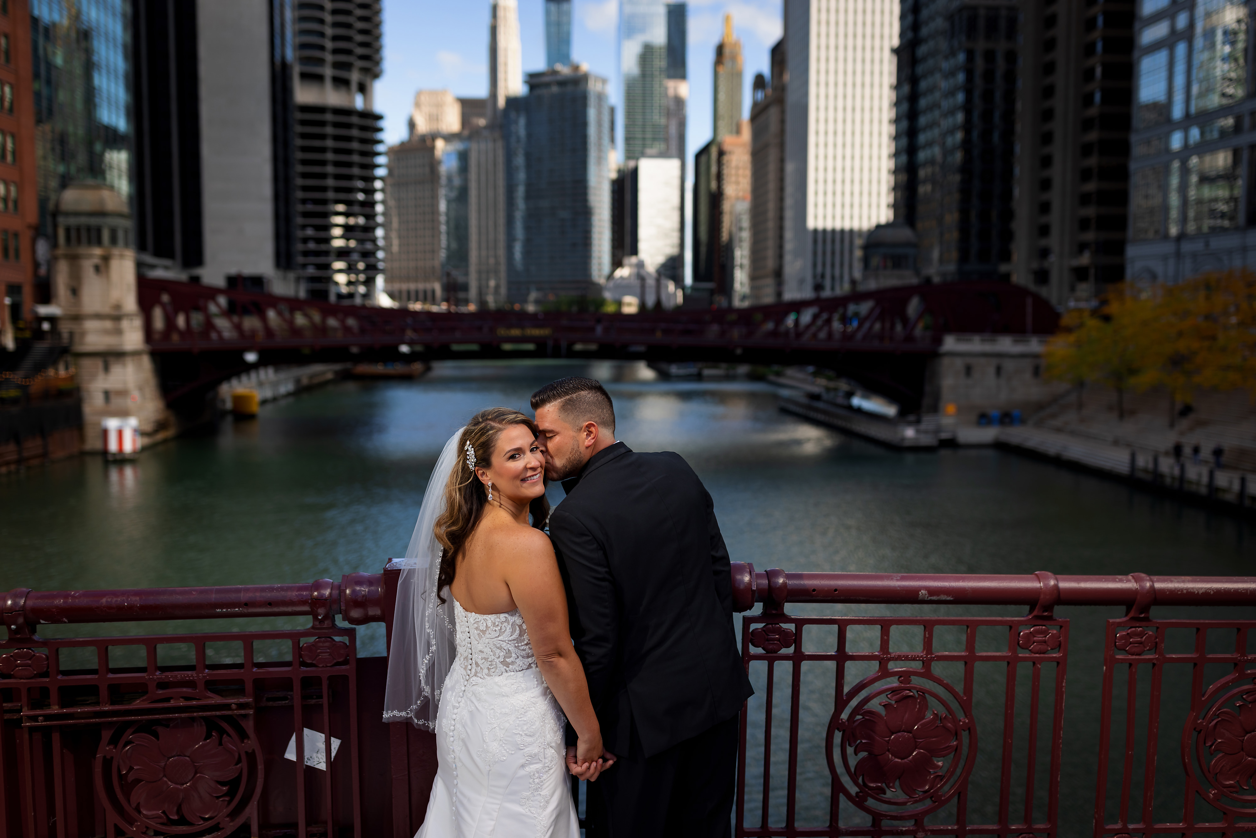 Bride and groom pose for a portrait on LaSalle street  Bridge in downtown Chicago during wedding portraits with river and skyline in the background.