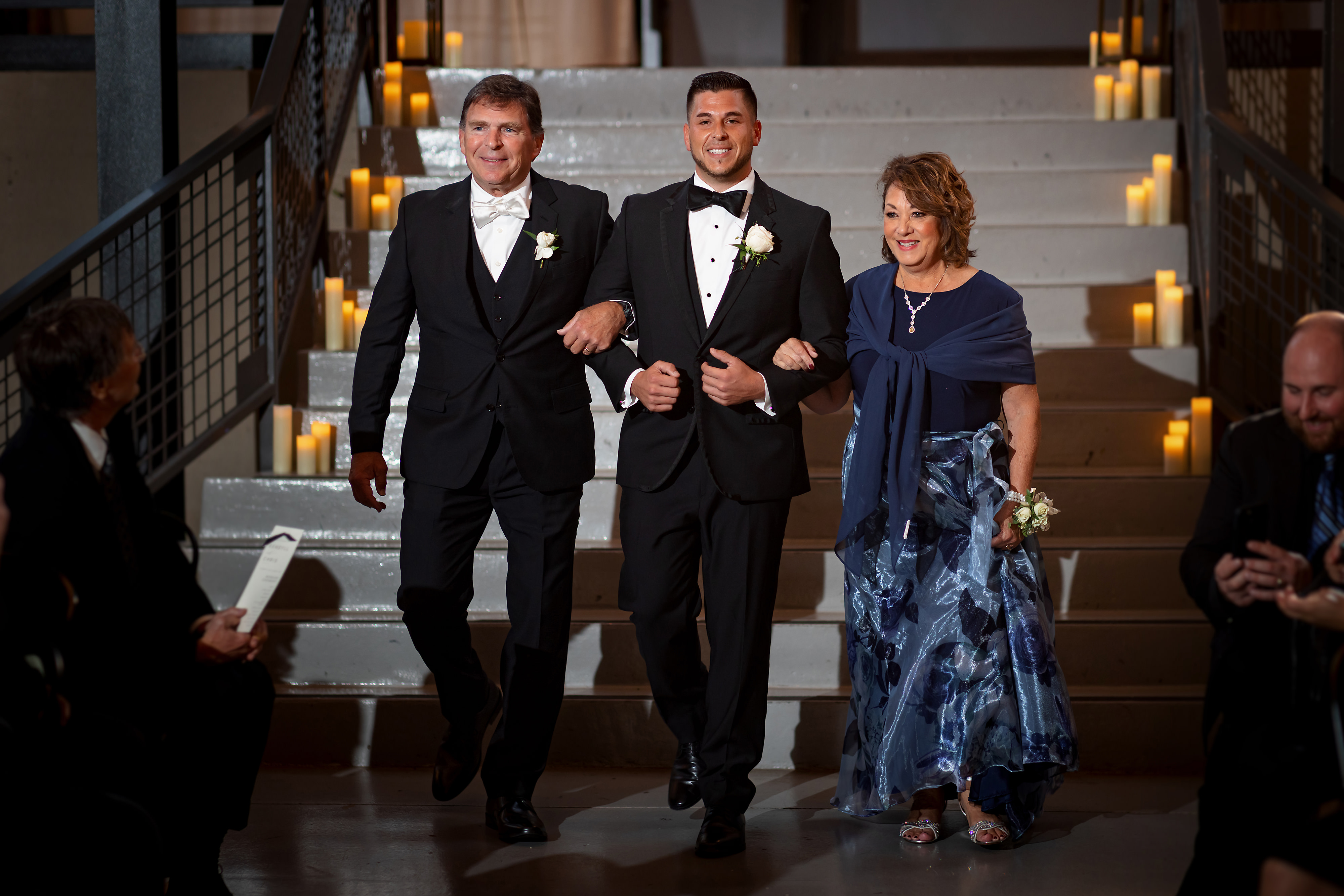 Groom walks down the aisle with parents during wedding ceremony at Artifact Events in Chicago's Ravenswood neighborhood.
