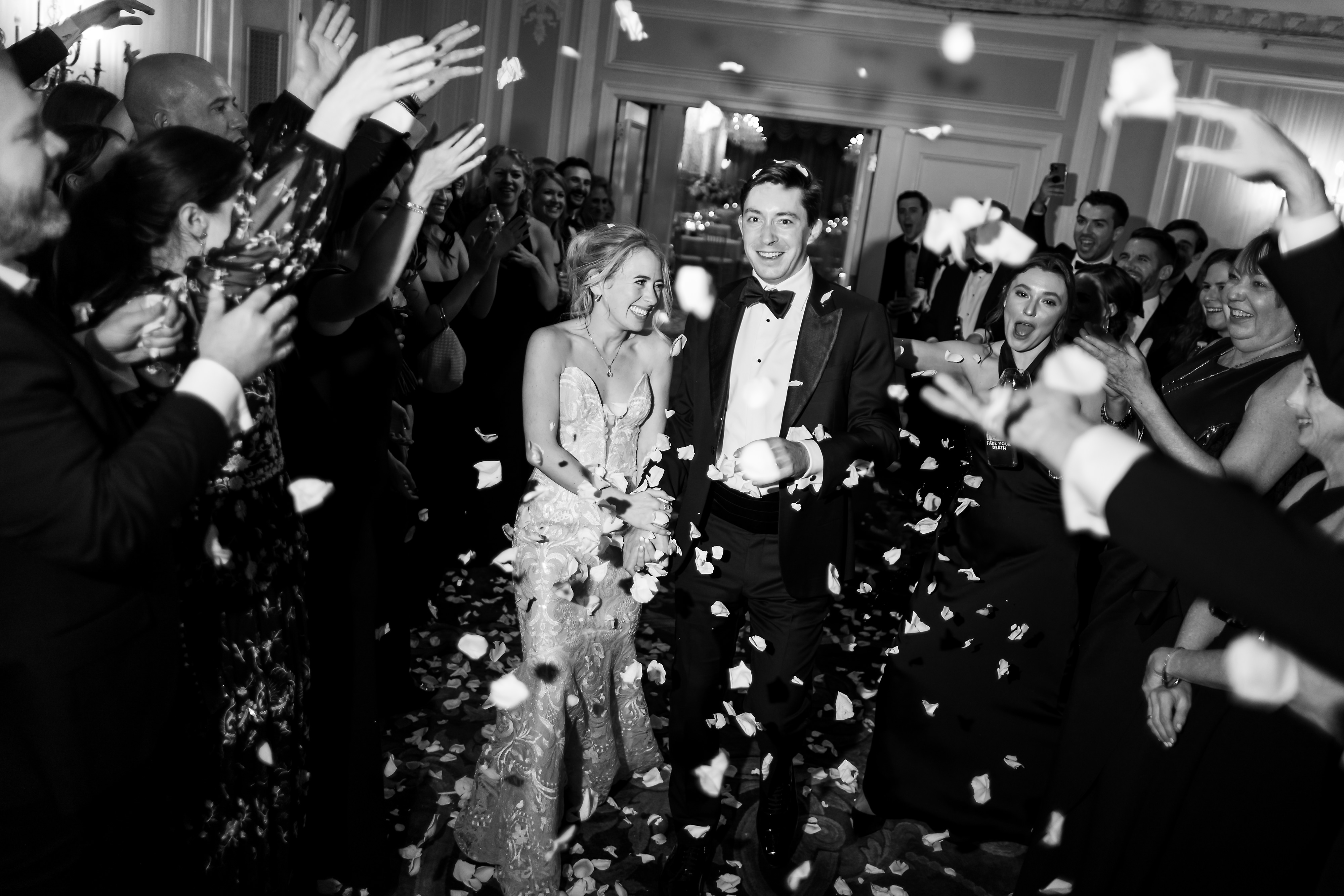 Bride and groom leave wedding reception as guest throw flower petals in the air