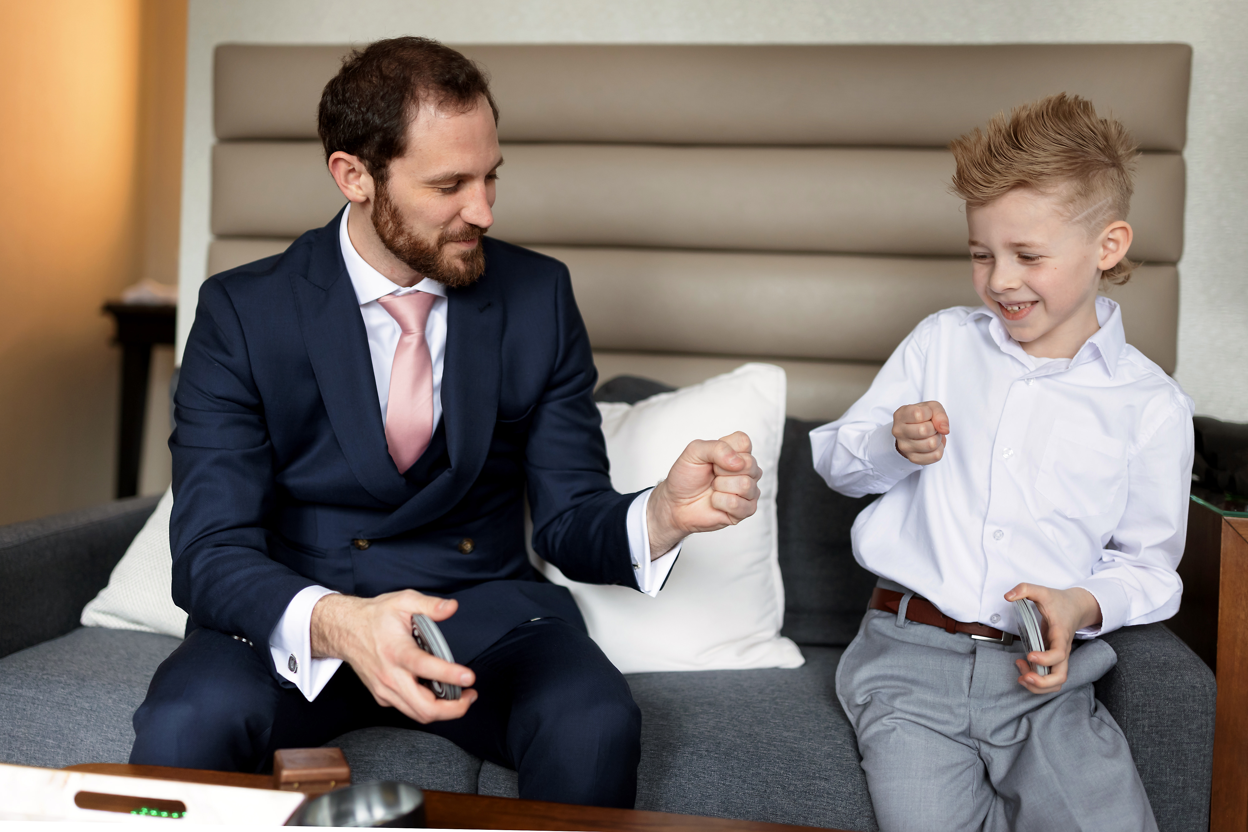 Groom and ring bearer play cards while getting ready for wedding