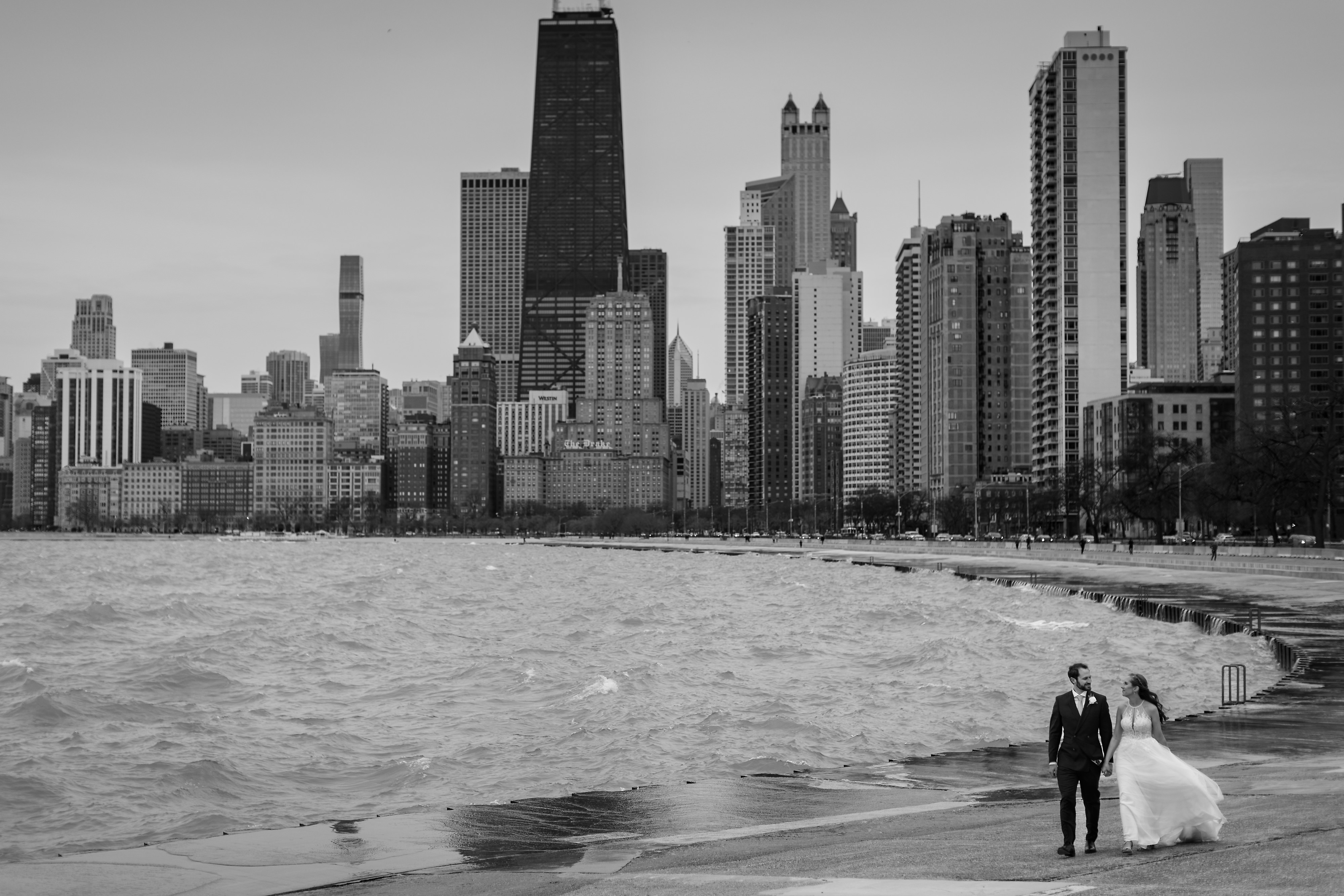 Bride and groom walk along the lakeshore at North Ave. Beach in Chicago