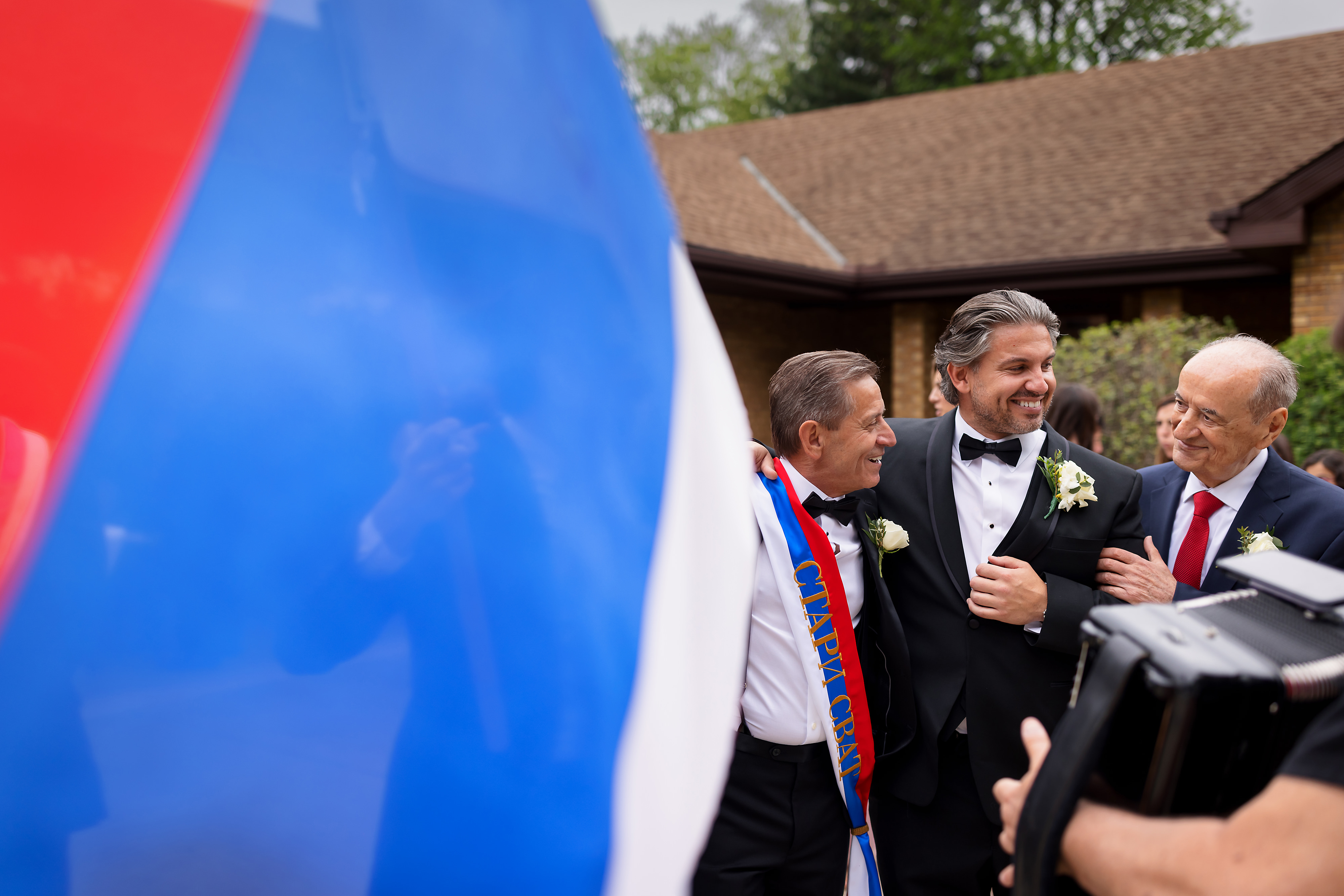 Groom and family with serbian flag in forground during skup