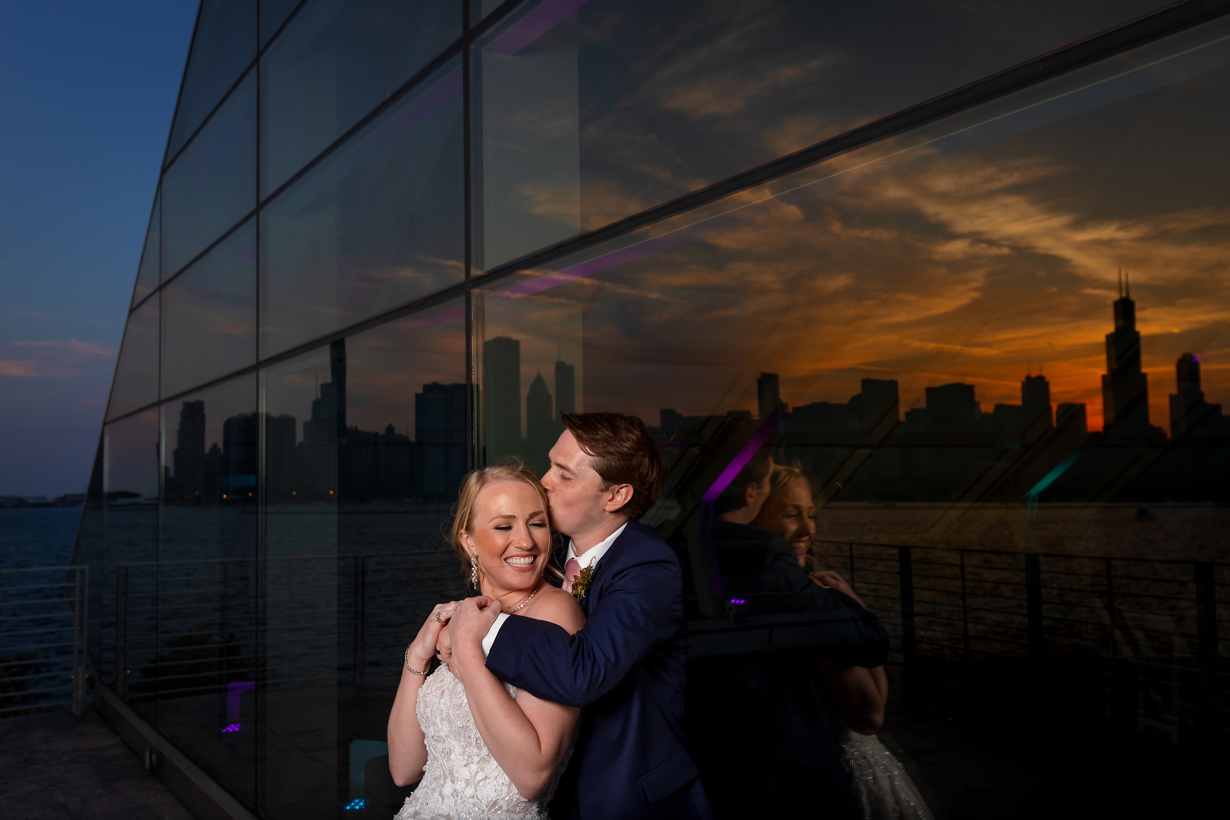 sunset portrait of bride and groom with reflection of city at Adler Planetarium in Chicago