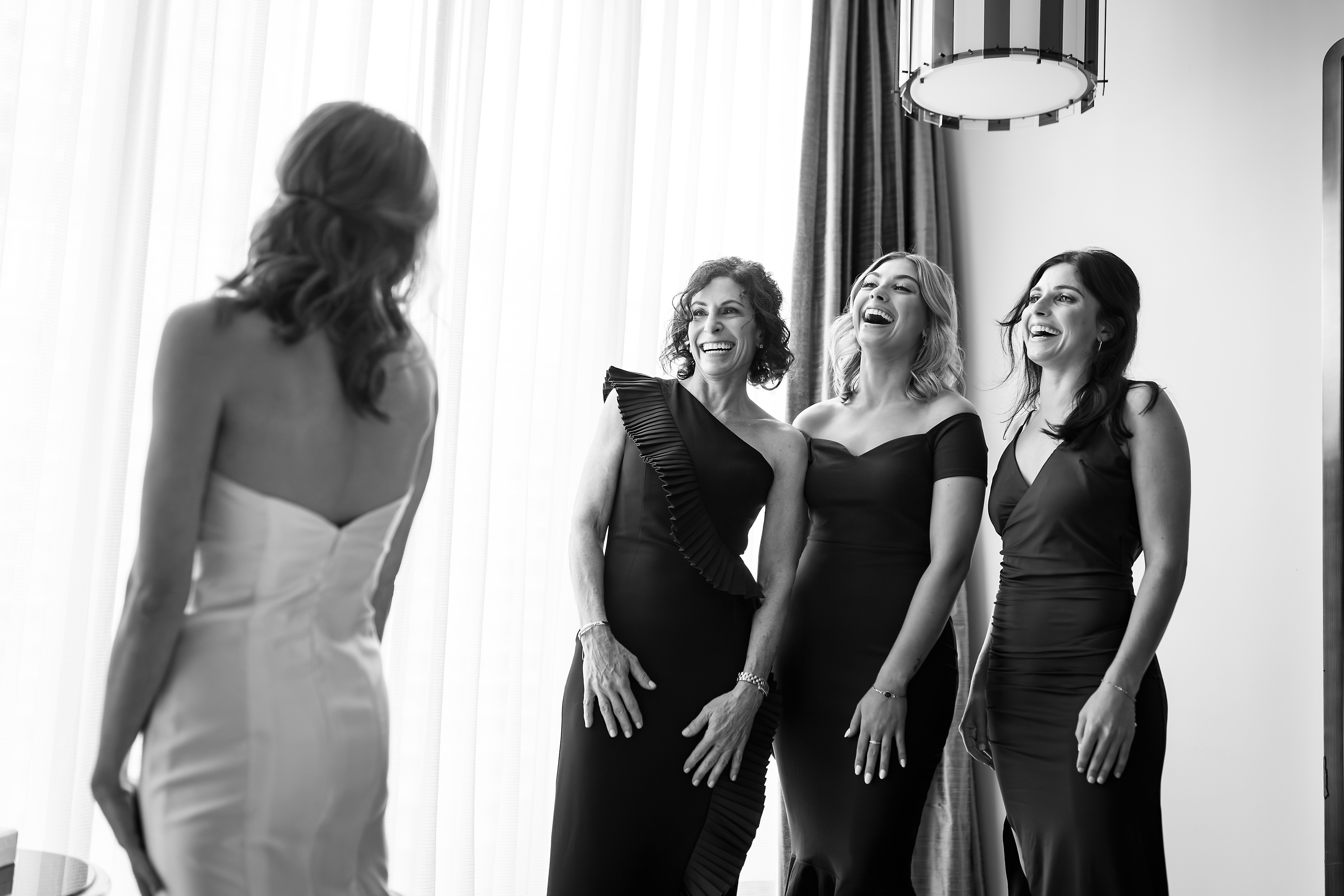 Bridesmaids laughing while bride gets ready