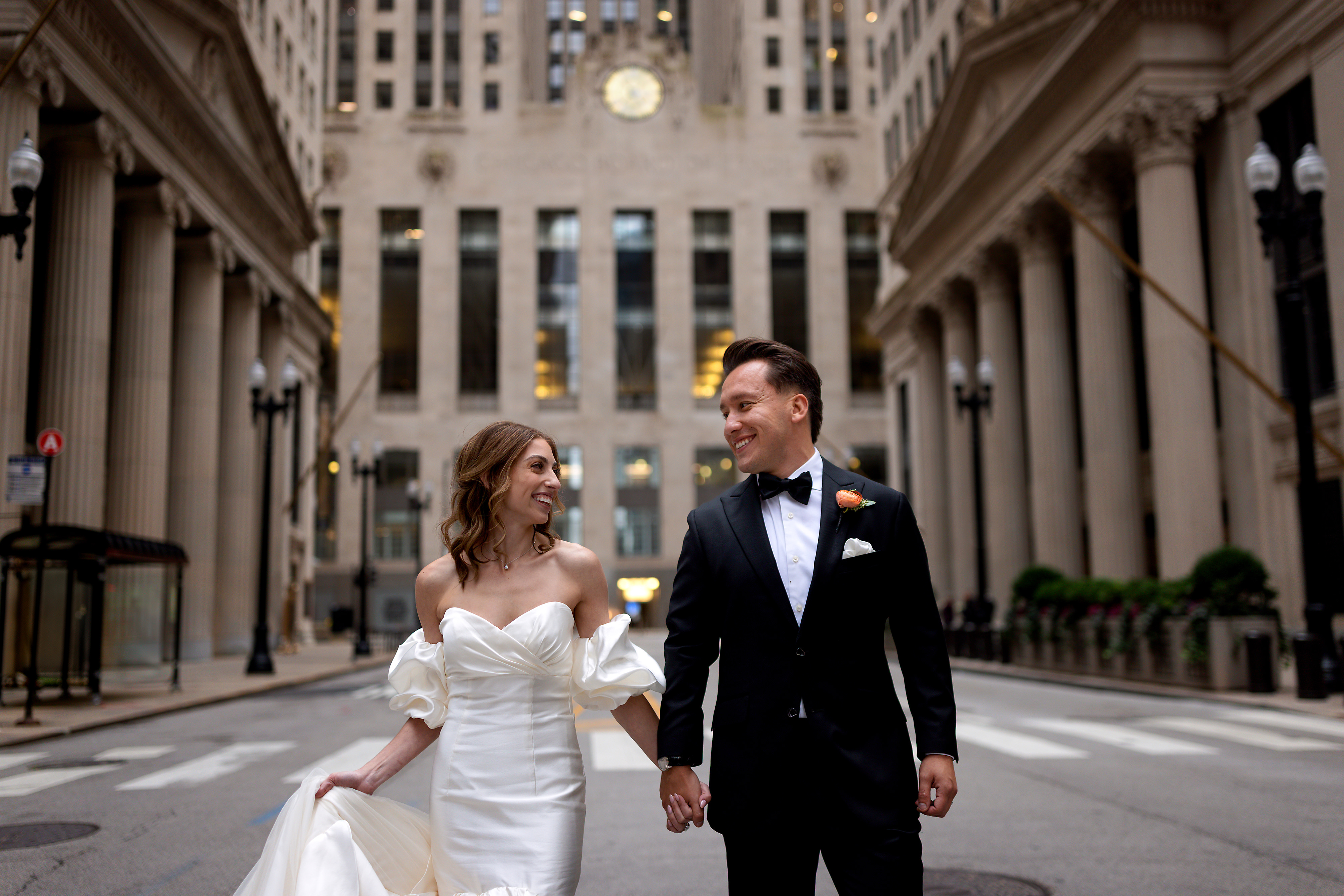 Bride and Groom walking down LaSalle Street in front of Board of Trade Building in Chicago