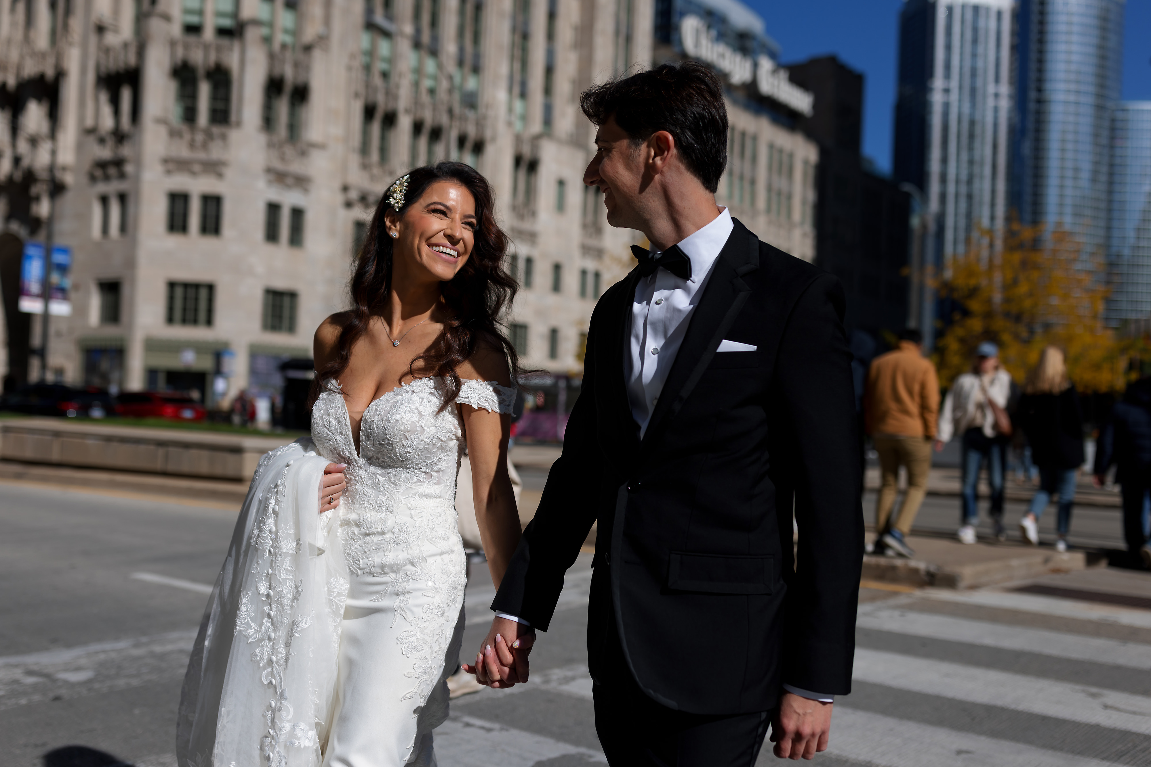 Bride and groom walk across Michigan Avenue with the Chicago Tribune building in the background