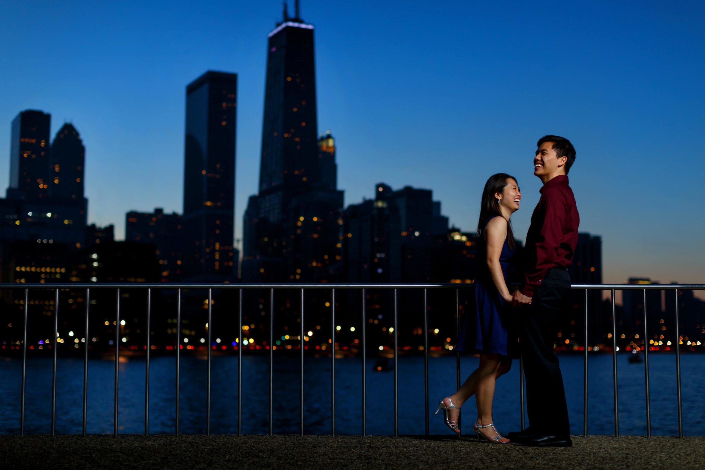 couple-laughs-during-Olive-Park-engagement-photos-with-Chicago-skyline-in-background-07